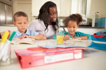 Mother Helping Children With Homework At Table
