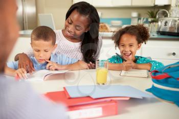 Mother Helping Children With Homework At Table