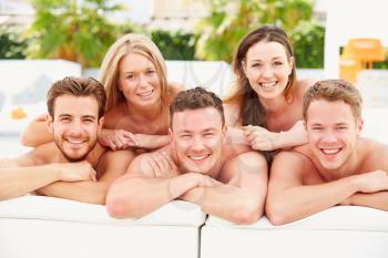 Group Of Young People On Holiday Relaxing By Swimming Pool