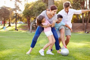 Family Playing Soccer In Park Together