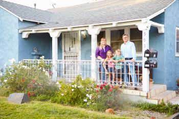 Portrait Of Family Standing On Porch Of Suburban Home
