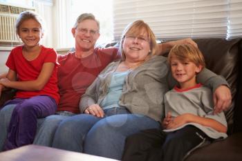 Portrait Of Happy Family Sitting On Sofa Together