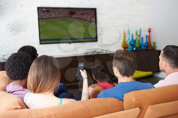 Group Of Friends Sitting On Sofa Watching Soccer Together