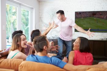 Group Of Friends Sitting On Sofa Watching Soccer Together