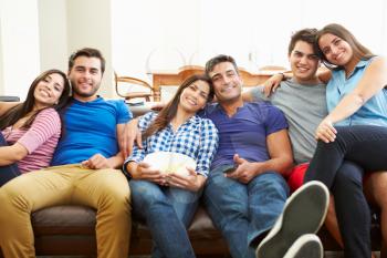 Group Of Friends Sitting On Sofa Watching TV Together