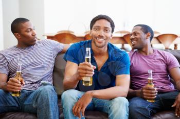 Group Of Men Sitting On Sofa Watching TV Together