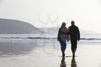 Senior Couple Walking Along Winter Beach