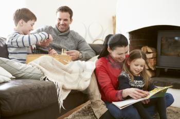 Family Relaxing Indoors Playing Chess And Reading Book