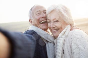 Senior Couple Standing On Beach Taking Selfie