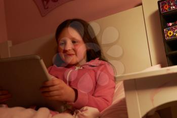Young Girl Using Digital Tablet In Bed At Night