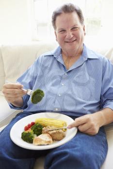 Overweight Man Eating Healthy Meal Sitting On Sofa