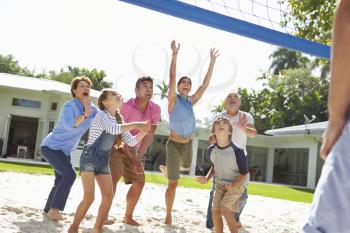 Multi Generation Family Playing Volleyball In Garden