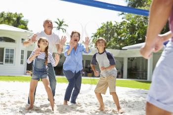 Grandparents And Grandchildren Playing Volleyball In Garden