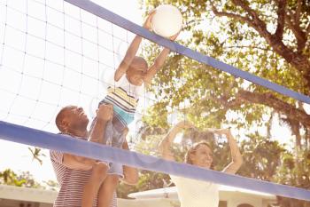 Family Playing Game Of Volleyball In Garden