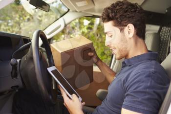 Delivery Driver Sitting In Van Using Digital Tablet