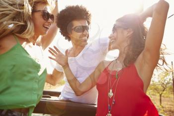 Group Of Young Friends Dancing In Back Of Open Top Car