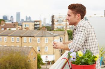 Man Relaxing Outdoors On Rooftop Garden Drinking Coffee