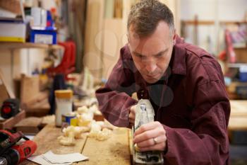 Carpenter Planing Wood In Workshop