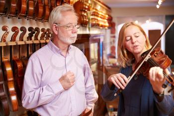 Customer Trying Out Violin In Music Store