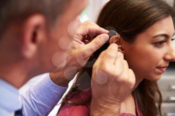 Doctor Fitting Female Patient With Hearing Aid