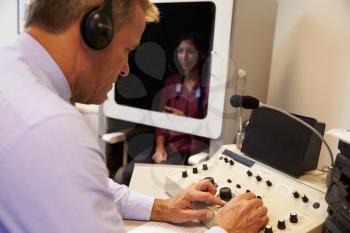 Audiologist Carrying Out Hearing Test On Female Patient