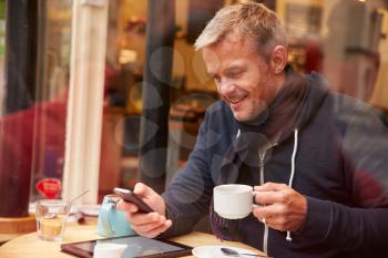 Man Viewed Through Window Of Caf Using Mobile Phone