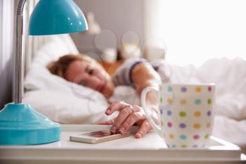 Sleeping Woman Being Woken By Mobile Phone In Bedroom