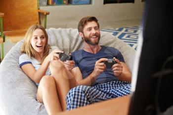 Young Couple In Pajamas Playing Video Game Together