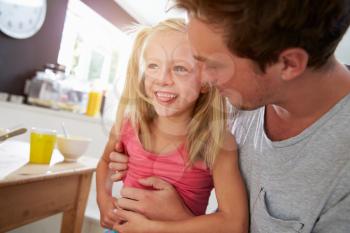 Father Sitting With Laughing Daughter At Breakfast Table