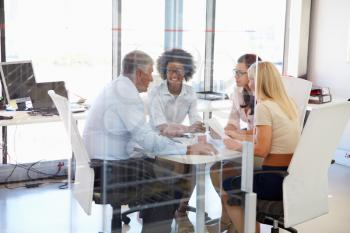 Four colleagues meeting around a table in an office