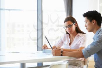 Two people working with digital tablet in empty meeting room