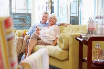 Senior Couple At Home Relaxing In Lounge With Cold Drinks