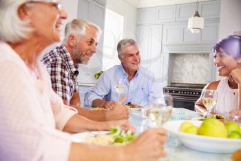 Group Of Mature Friends Enjoying Meal At Home Together