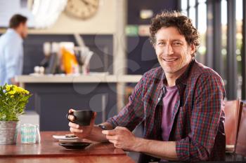 Man at coffee shop using phone, portrait