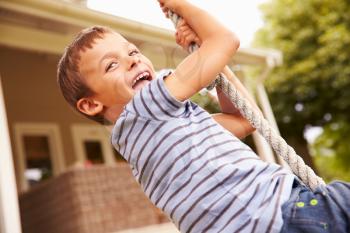 Smiling boy swinging on a rope at a playground