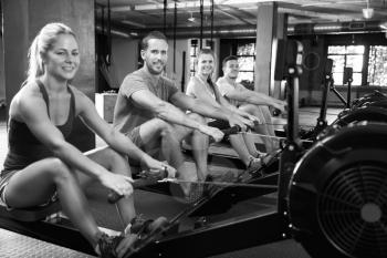 Black And White Shot Of Gym Class Using Rowing Machines
