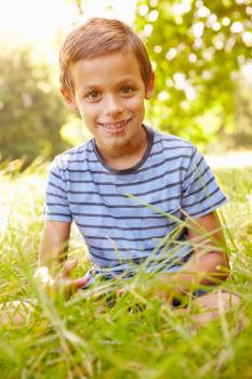 Portrait of a young boy sitting outdoors on a sunny day