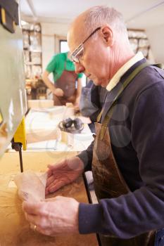 Senior shoemaker shaping shoe lasts in a workshop