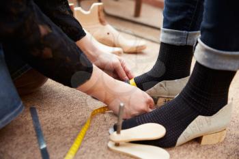 Shoemaker measuring customers feet, close up