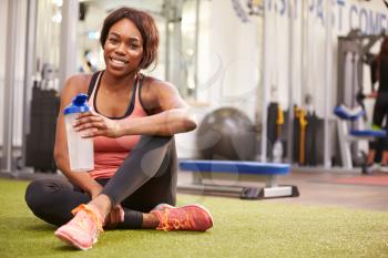 Young woman drinking water in a gym, with copy space
