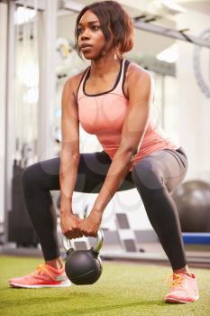 Woman exercising in a gym with a kettlebell weight, vertical