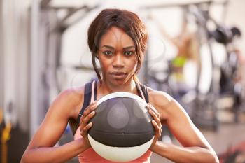 Portrait of a woman holding a medicine ball at a gym