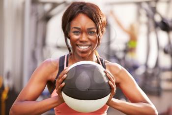 Portrait of a smiling woman holding a medicine ball at a gym