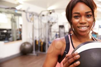 Portrait of a smiling woman holding a medicine ball at a gym, copy space