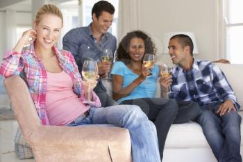Group Of Friends Relaxing On Sofa Drinking Wine At Home Together