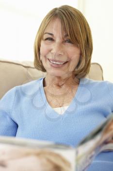 Senior Hispanic Woman Relaxing At Home With Magazine