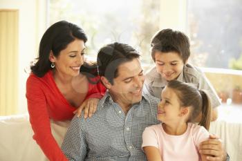 Young Hispanic Family Relaxing On Sofa At Home