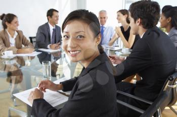 Asian Businesswoman Sitting Around Boardroom Table With Colleagues