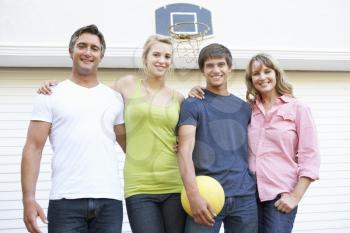 Portrait Of Teenage Family Playing Basketball Outside Garage