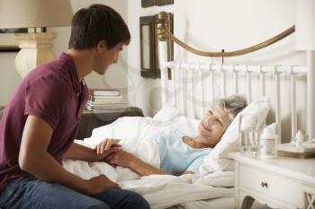 Teenage Grandson Visiting Grandmother In Bed At Home